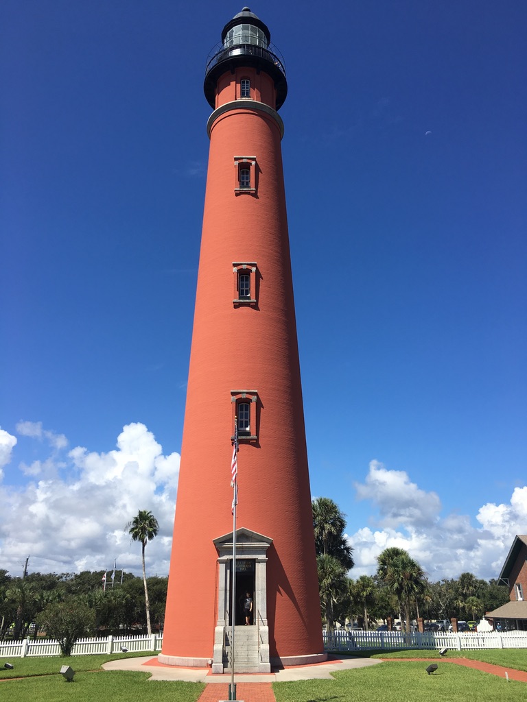 Ponce Inlet Lighthouse rising above palm trees and blue sky